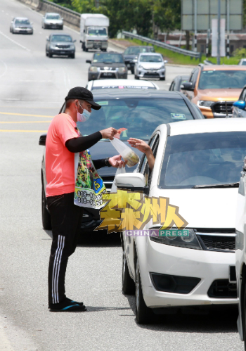 在炎日的下午,兜售者通过走入车龙中,向民众兜售芒果酸。